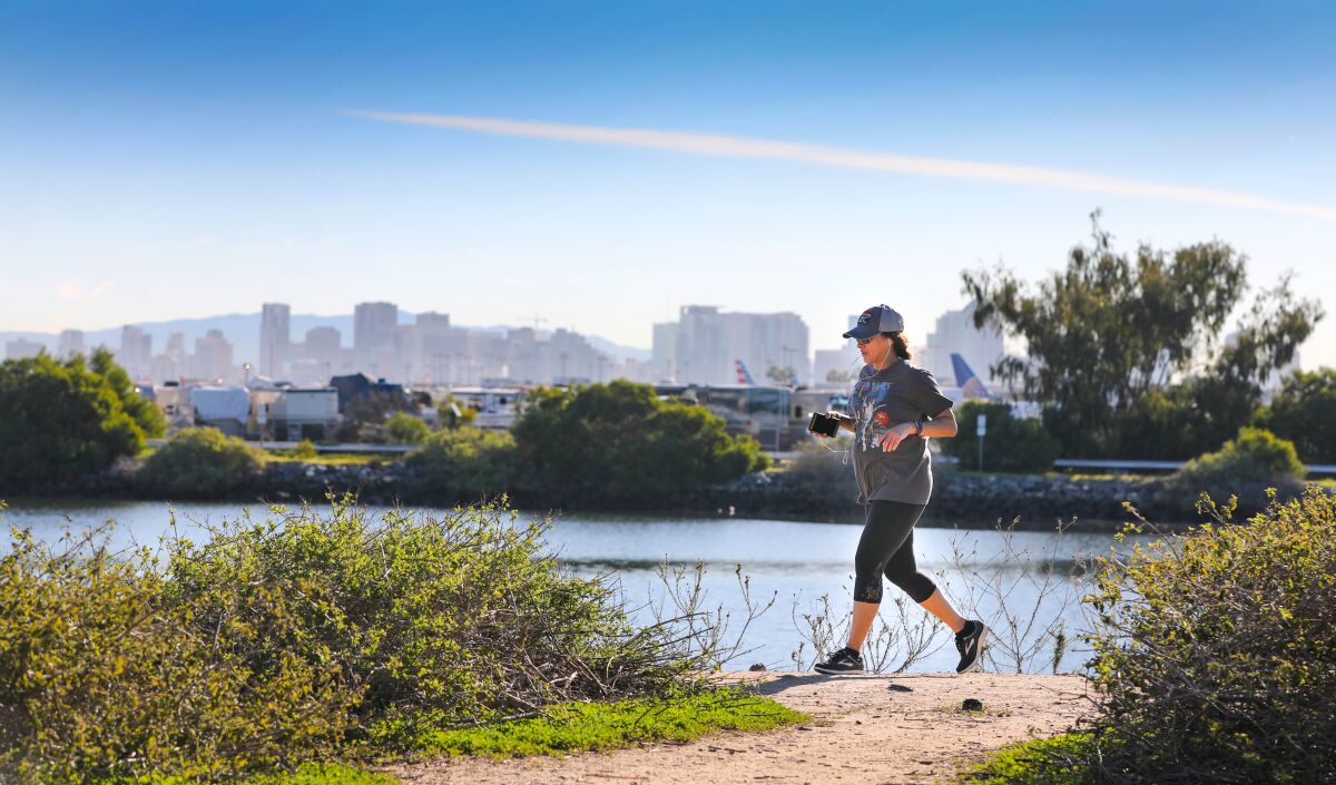 San Diego County unemployment stayed low at 2.8 percent in December. Pictured: With San Diego Bay, the San Diego International Airport and the San Diego downtown skyline as a backdrop, a visitor to Liberty Station jogs along a path that runs along San Diego Bay, January 7, 2020.