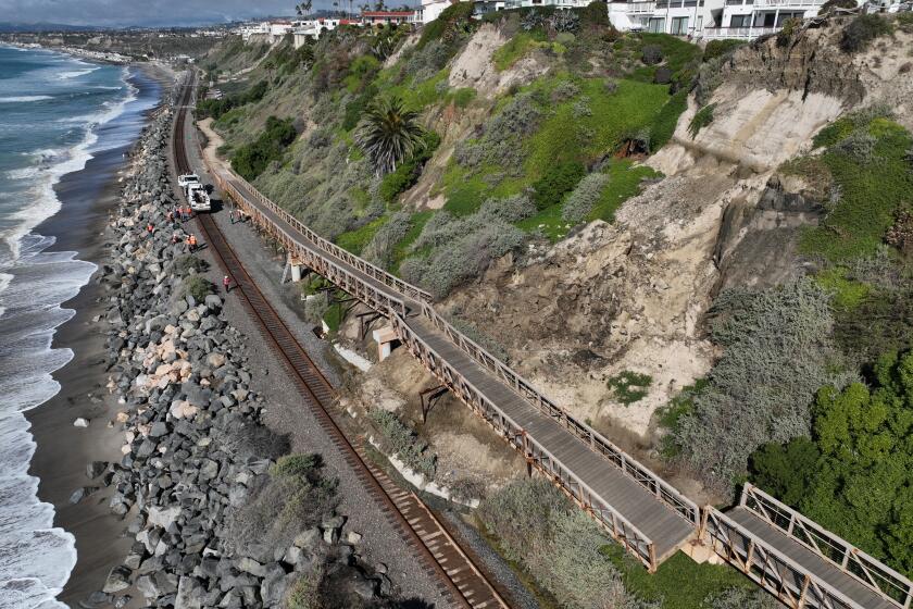 San Clemente, CA - January 25: An aerial view of Metrolink workers surveying a landslide that partially covered the train tracks and damage the Mariposa Trail Bridge, north of the San Clemente Pier in San Clemente Thursday, Jan. 25, 2024. Passenger rail service between the Laguna Niguel/Mission Viejo and Oceanside stations was suspended due to boulders and debris falling onto the tracks caused by a landslide damaging the Mariposa Trail Bridge in San Clemente, Metrolink announced, and it was uncertain today when service would resume. (Allen J. Schaben / Los Angeles Times)