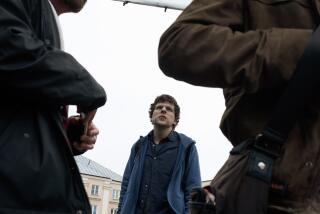 A man in a blue shirt stands on a movie set.