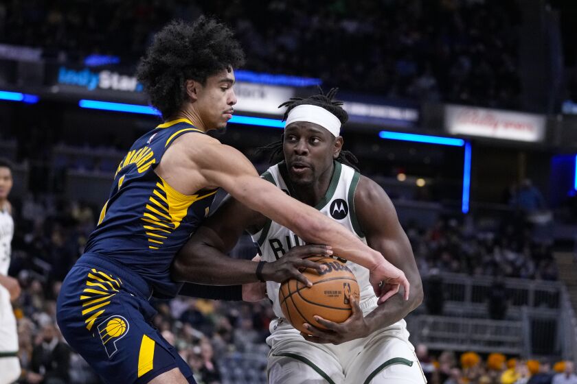 Indiana Pacers guard Andrew Nembhard (2) ties up Milwaukee Bucks guard Jrue Holiday (21) during the second half of an NBA basketball game in Indianapolis, Wednesday, March 29, 2023. (AP Photo/Michael Conroy)