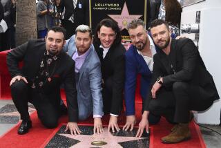 NSYNC's Chris Kirkpatrick, Lance Bass, JC Chasez, Joey Fatone and Justin Timberlake smile and crouch by a Walk of Fame star