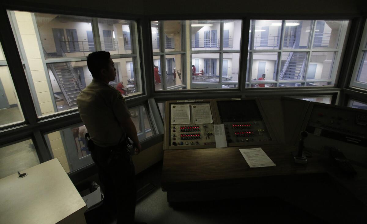 A Fresno County sheriff's deputy looks over a jail holding block inside a control center.