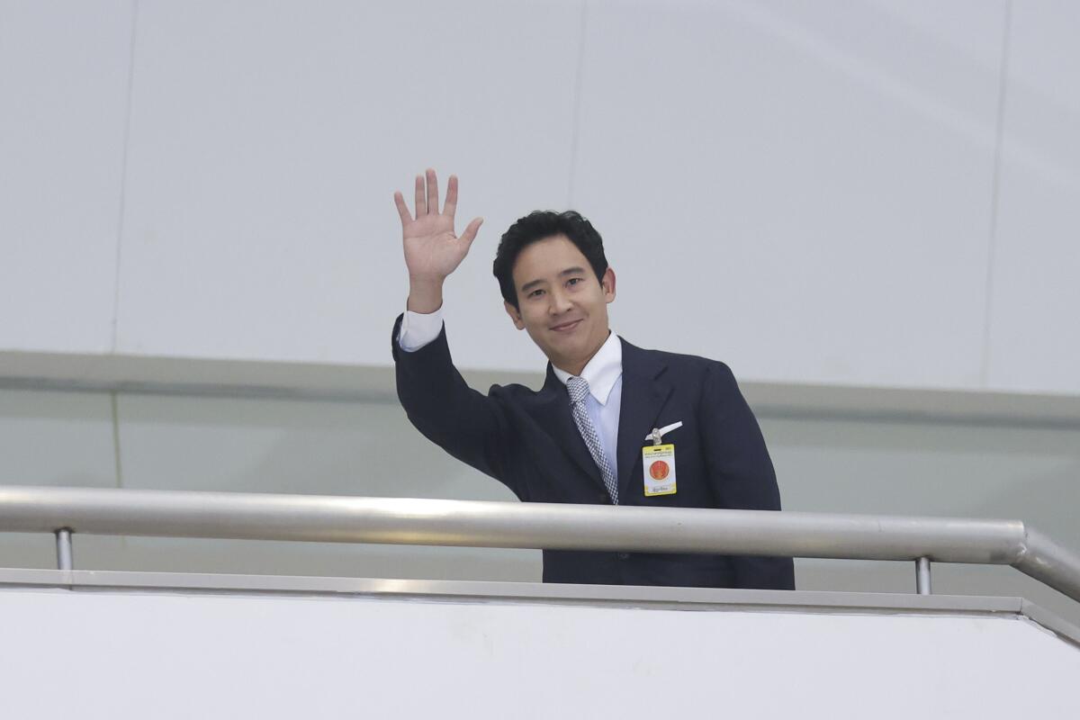 A man waves from behind a stair railing.