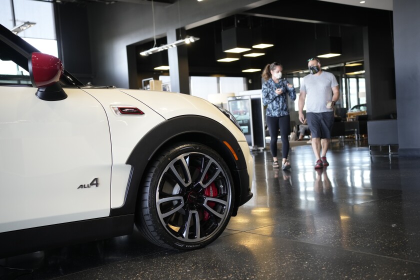Customers move past a 2022 Clubman John Cooper Works model for sale on the floor of a Mini showroom Saturday, Aug. 21, 2021, in Highlands Ranch, Colo. Retail sales took an unexpected dip in December 2021 in what could be a signal that the increasing weight of persistently rising inflation is prompting a pullback in consumer spending. (AP Photo/David Zalubowski)