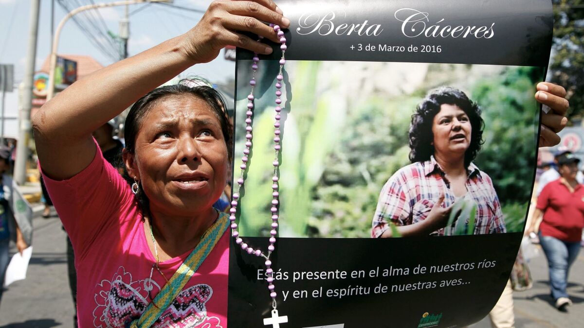 A woman holds up a poster of a slain environmentalist and indigenous rights activist during a protest march in Tegucigalpa, Honduras.