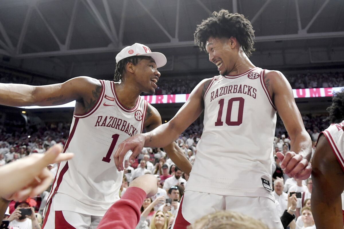 Arkansas players JD Notae (1) and Jaylin Williams (10) celebrate with fans after defeating Auburn 80-76 in overtime during an NCAA college basketball game Tuesday, Feb. 8, 2022, in Fayetteville, Ark. (AP Photo/Michael Woods)