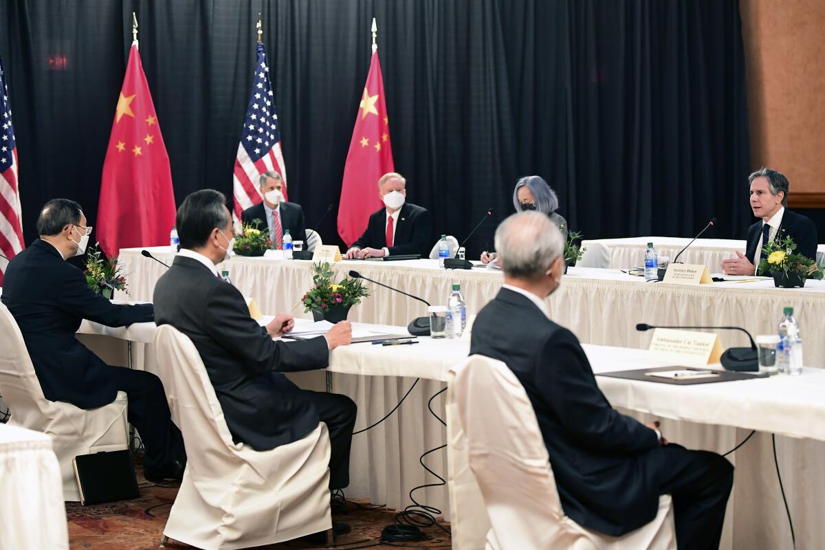 Secretary of State Antony Blinken speaks across a table to Chinese officials.