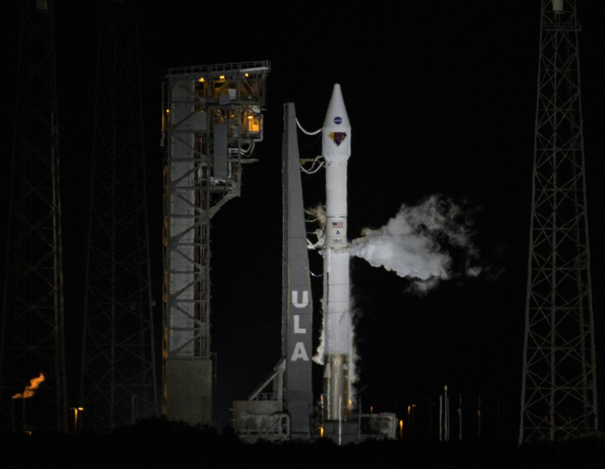 A rocket stands on its launchpad next to service gantry at night shortly before its launch from Cape Canaveral, Fla.