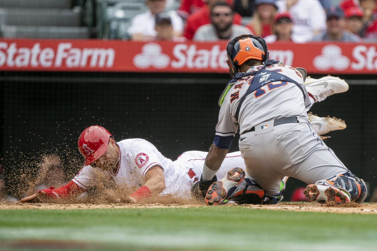 Houston Astros catcher Martin Maldonado, right, tries to tag Angels baserunner Tyler Wade at home plate.