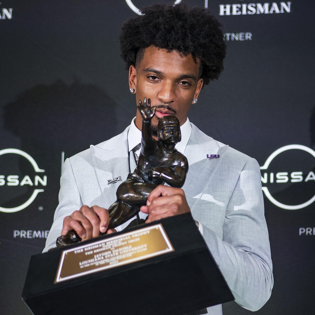 LSU quarterback Jayden Daniels kisses the Heisman Trophy during a news conference.