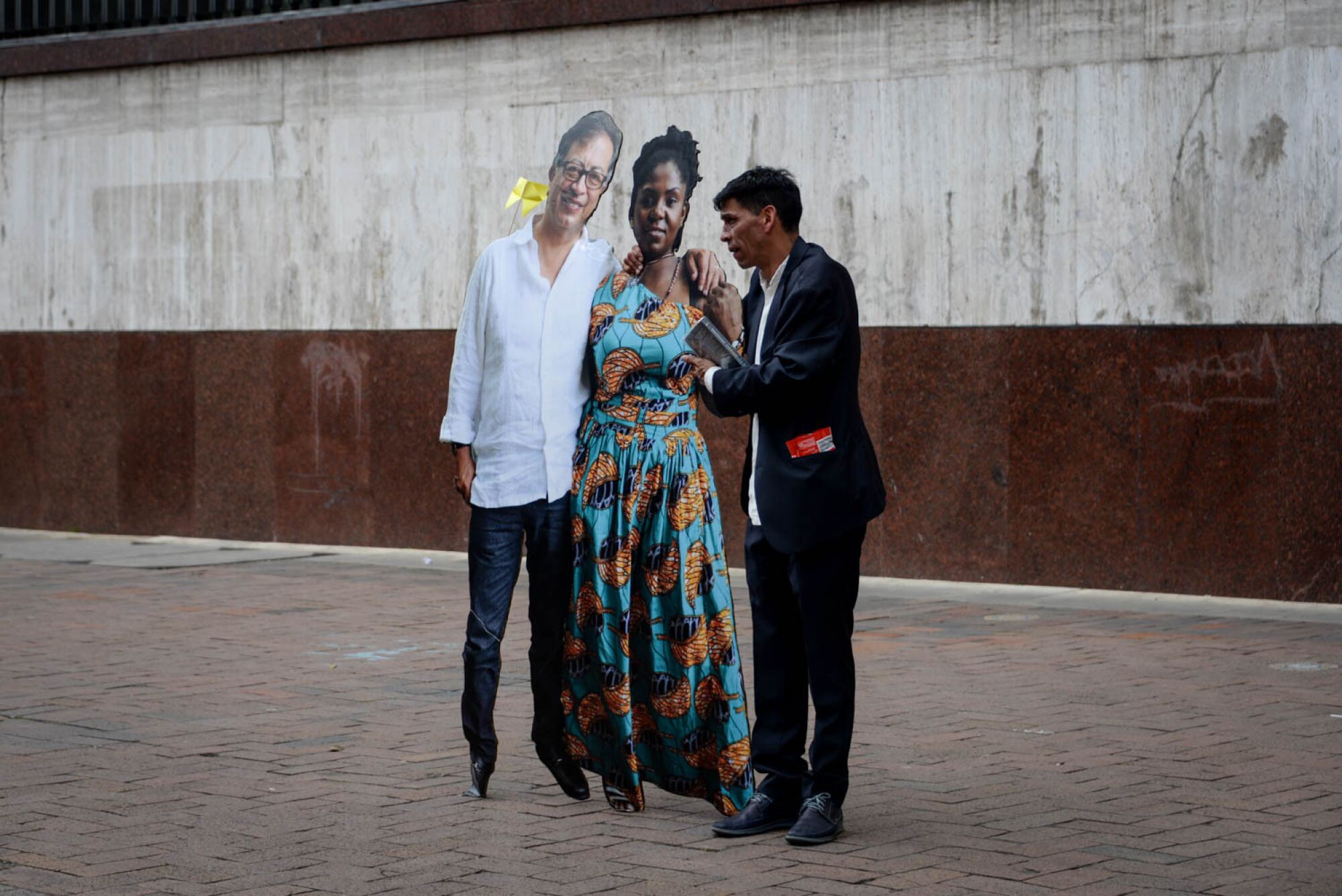 A man holds a cardboard cutout of Colombia's president and vice president