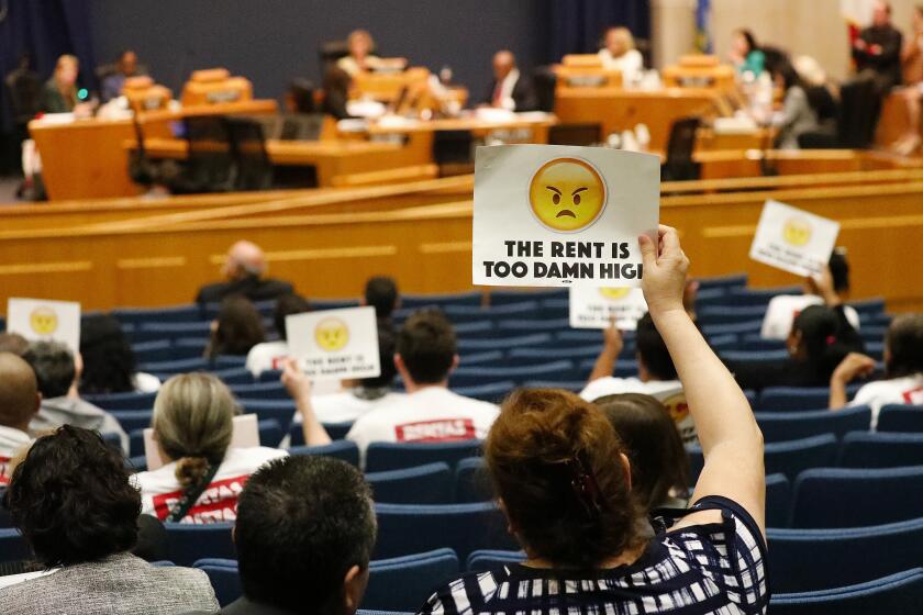 Al Seib  Los Angeles Times BEATRICE SANDOVAL holds up a sign at an L.A. County Board of Supervisors meeting in April. A new law signed Tuesday will hold most annual rent increases in California to 5% plus inflation over the next 10 years.