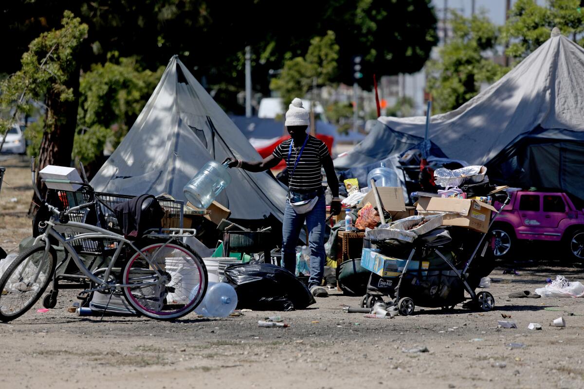 A homeless encampment with tents, bikes, carts and scattered items