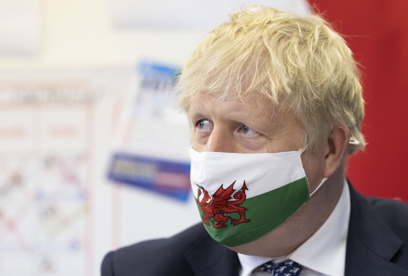 Britain's Prime Minister Boris Johnson wears a Welsh flag face mask during a visit to Barry Island, Wales, as part of the Welsh Conservative Party's Senedd election campaign, Monday, May 3, 2021. (Matthew Horwood/PA via AP)