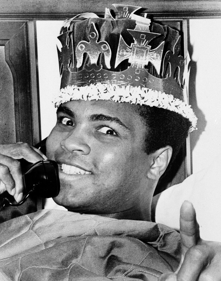 FILE - Muhammad Ali wears a crown while speaking on the phone in Miami Beach, Fla., ahead of his March 8 fight against Joe Frazier in New York, in this March 6, 1971, file photo. Their first fight at Madison Square Garden was so epic it was billed as the Fight of the Century, and 50 years later it reigns undefeated. (AP Photo/Joe Migon, File)