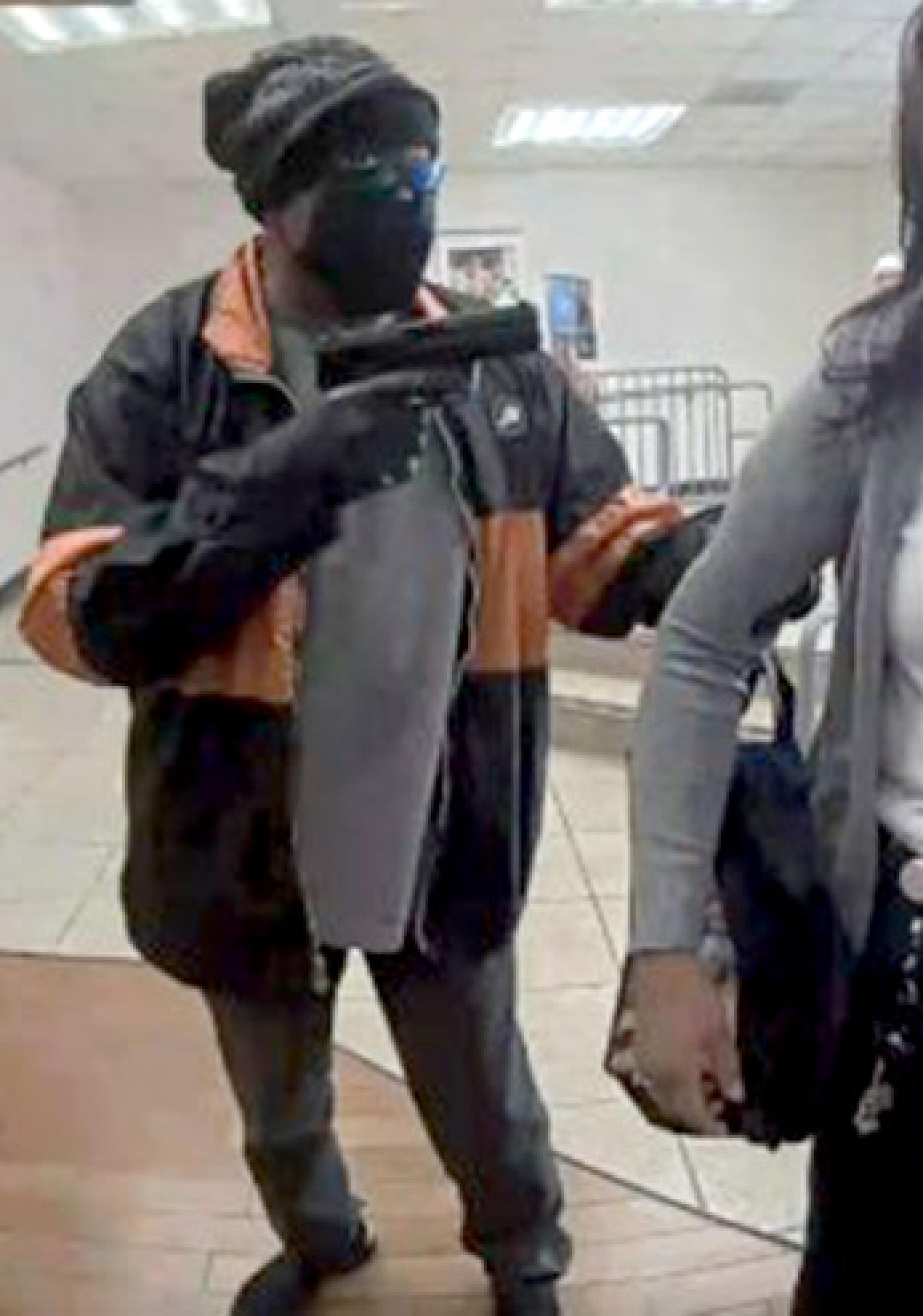 A masked bank robber holds a weapon.