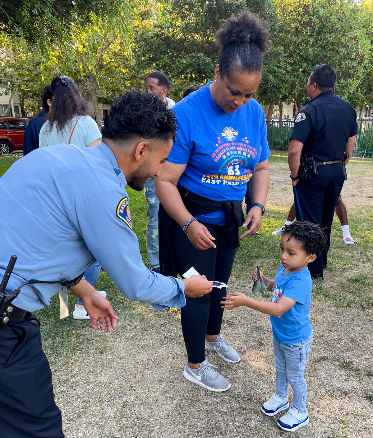 Community Service Officer Magd Algaheim giving a young community member a sticker during a National Night Out party