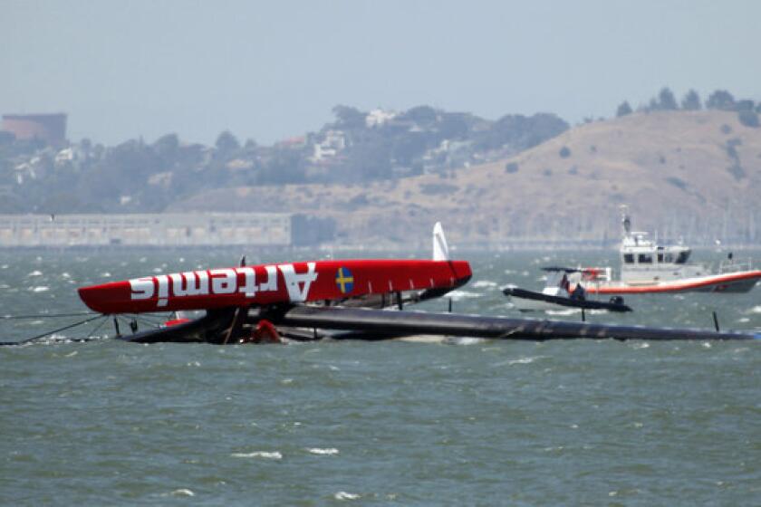 The overturned Artemis Racing AC72 catamaran, an America's Cup entry from Sweden, is towed past Treasure Island after the boat capsized during training in San Francisco Bay .