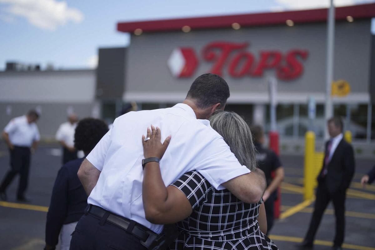 A man hugs a woman in the lot outside a store. 