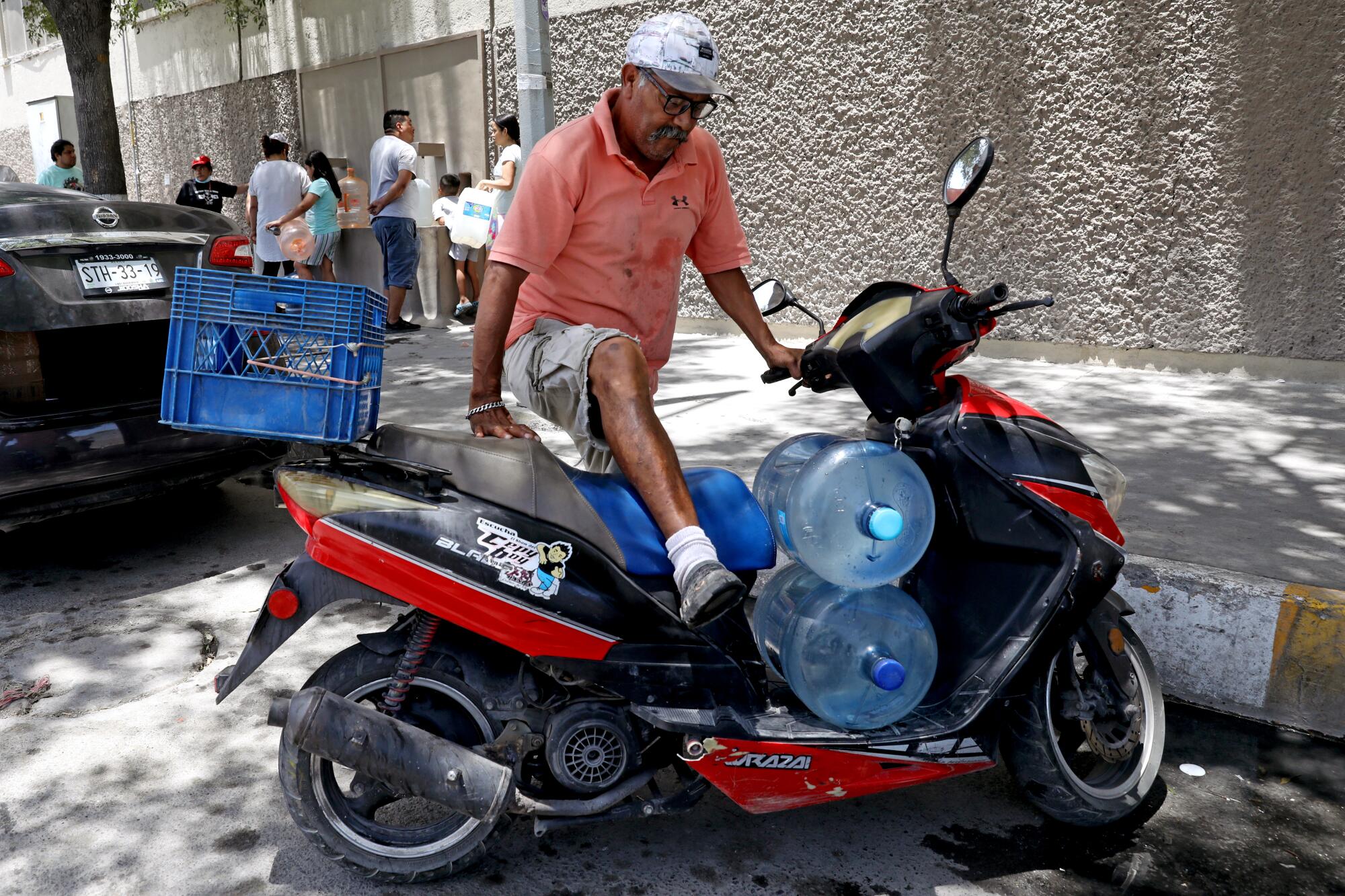 A man with large water bottles on a parked motorcycle
