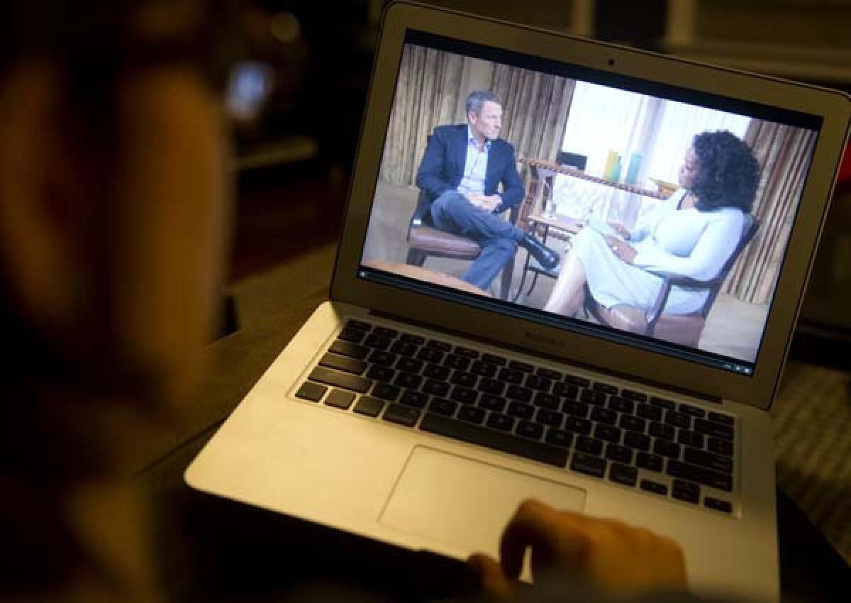 A woman watches on her computer as Oprah Winfrey questions cyclist Lance Armstrong during an interview recorded on Monday and shown on Thursday night.