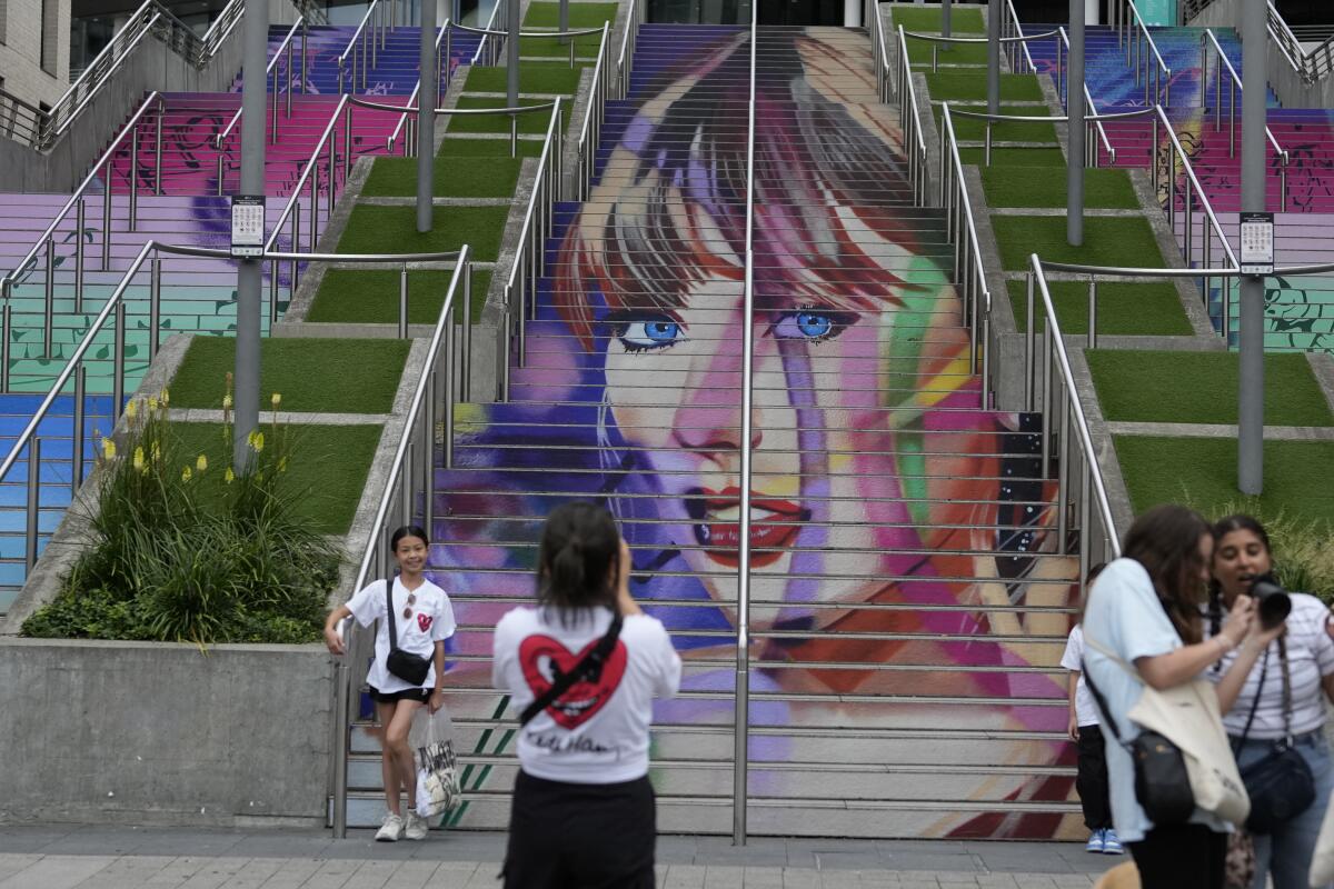 Fans posan junto a un retrato de Taylor Swift pintado en una escalera 