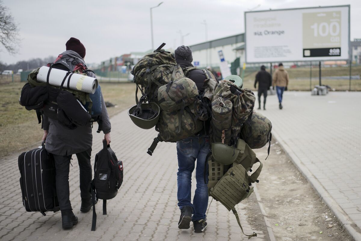 A man carries combat gear as he leaves Poland to fight in Ukraine.