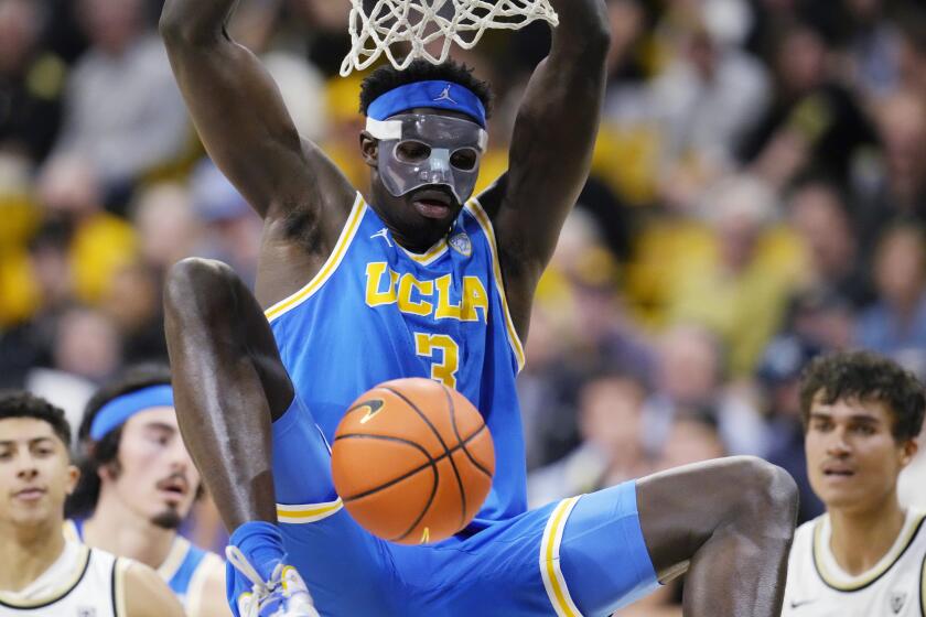 UCLA forward Adem Bona hangs from the rim after dunking the ball for a basket in the first half of an NCAA college basketball game against Colorado Sunday, Feb. 26, 2023, in Denver. (AP Photo/David Zalubowski)