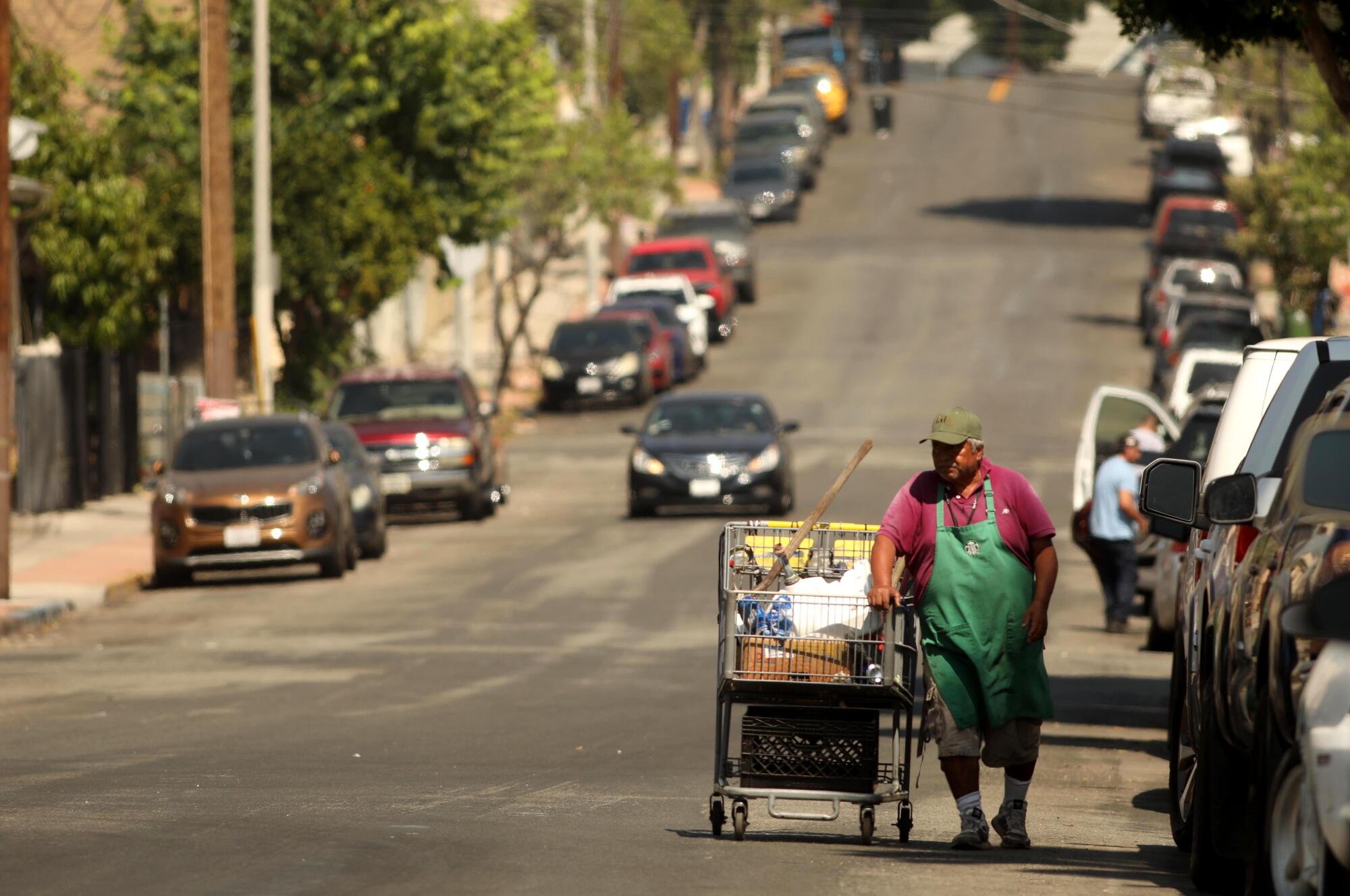 A man walks with a shopping cart looking for recyclables in Boyle Heights.
