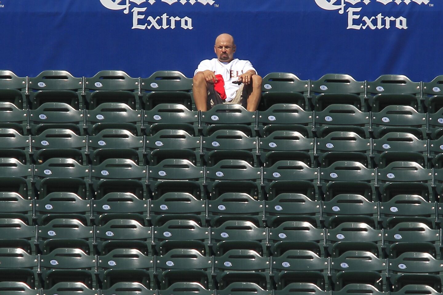 A man has a large section of the left field bleachers to himself as the heat kept many away from Angels Stadium for the game against the Houston Astros on Sunday.
