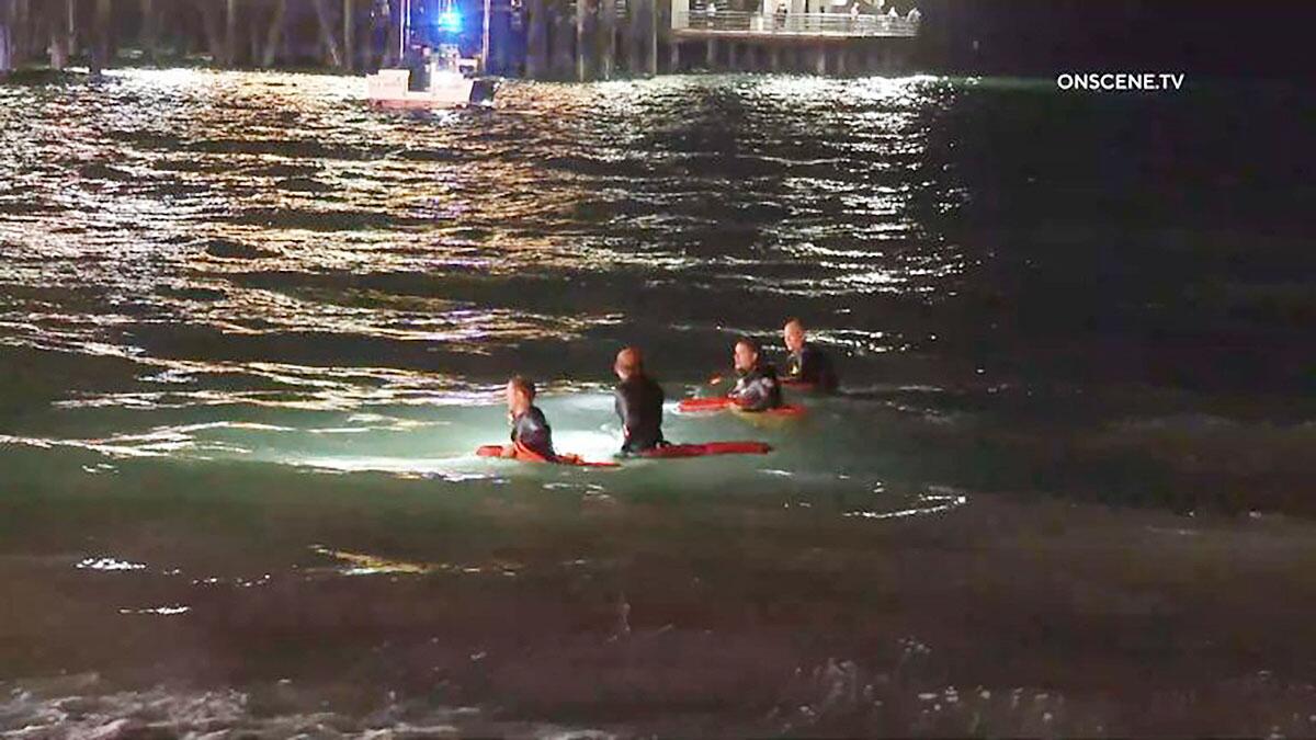 Lifeguards search the water near the Santa Monica Pier at night. 