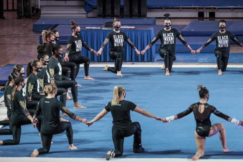Westwood, CA, Saturday, February 27, 2021 - UCLA gymnasts join hands during a prematch ceremony honoring the Black Lives Matter movement before a meet against Oregon State at Pauley Pavilion. (Robert Gauthier/Los Angeles Times)
