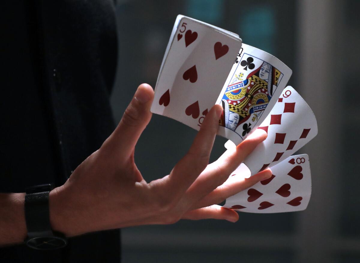 A close-up shot of a hand holding four different playing cards.