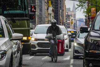 FILE - A food delivery worker rides through the a busy street in lower Manhattan, Friday, April 28, 2023, in New York. In a national first, New York City will implement a minimum pay rate for app-based food delivery workers, officials said in June 2023. (AP Photo/Bebeto Matthews, File)