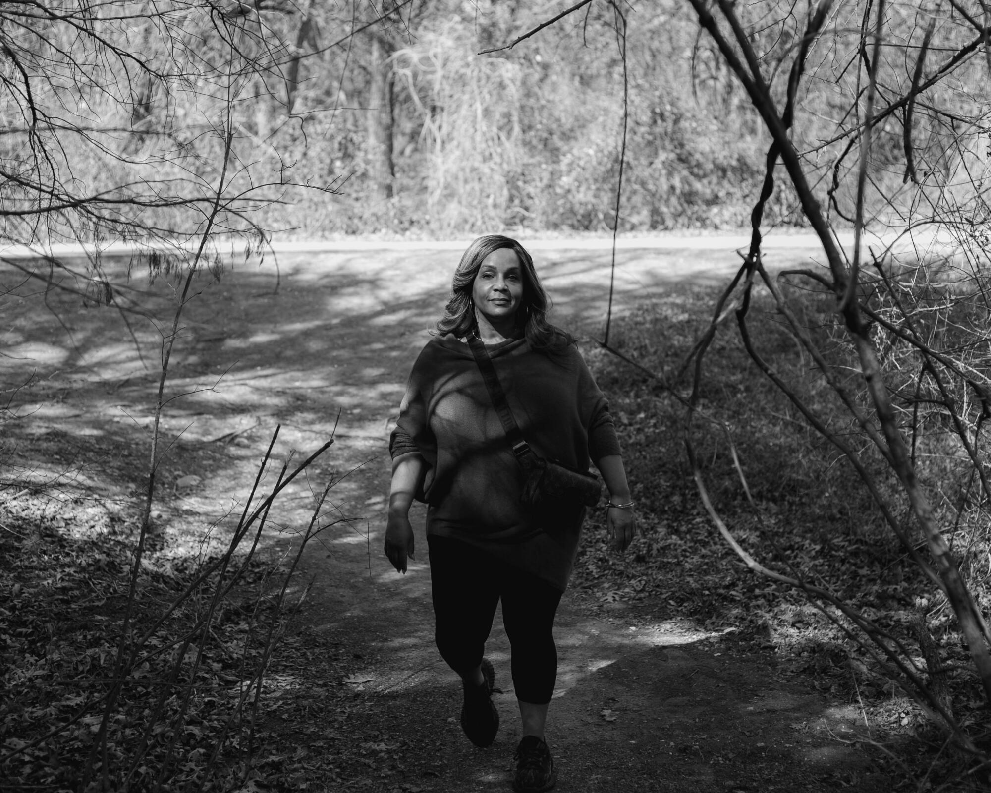 A woman with a cross bag and surrounded by branches walks forward