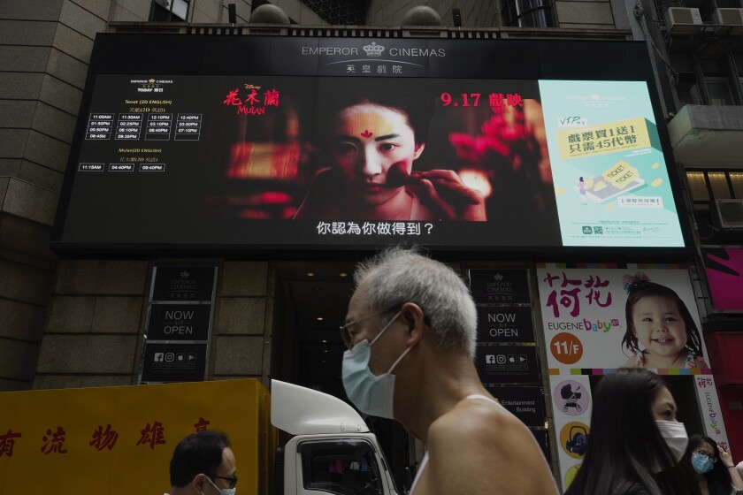 FILE-In this Thursday, Sept. 17, 2020, file, People walk past a huge TV screen showing movie listings "along a downtown street in Hong Kong. Hong Kong censors now have the power to ban films that endanger national security, prompting concerns that freedom of expression is being further curtailed in a city once known for its vibrant arts and film scene. (AP Photo/Vincent Yu, File)
