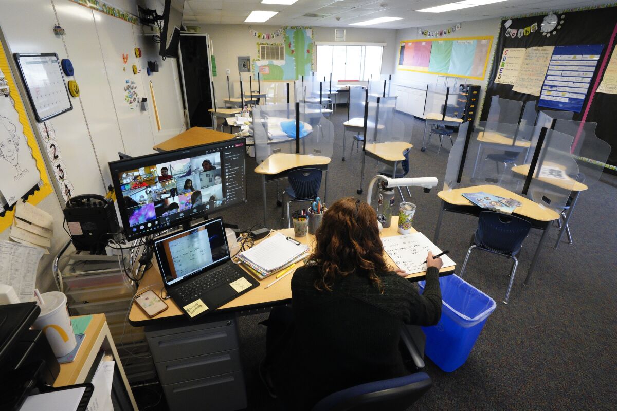 Samantha Thompson teaches 3rd grade students remotely from a classroom where empty desks are separated