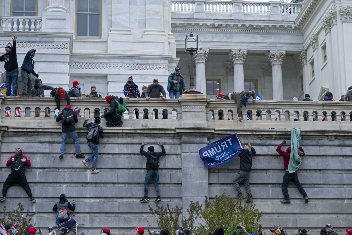FILE - In this Jan. 6, 2021 file photo, rioters climb the west wall of the the U.S. Capitol in Washington. First, some blamed the deadly Jan. 6 attack on the Capitol on left-wing Antifa antagonists, a theory quickly debunked. Then came comparisons of the rioters as peaceful protesters, or even “tourists." Now, Trump allies rallying in support of those people charged in the Capitol riot are calling them “political prisoners," a stunning effort to revise the narrative of that deadly day. (AP Photo/Jose Luis Magana, File)