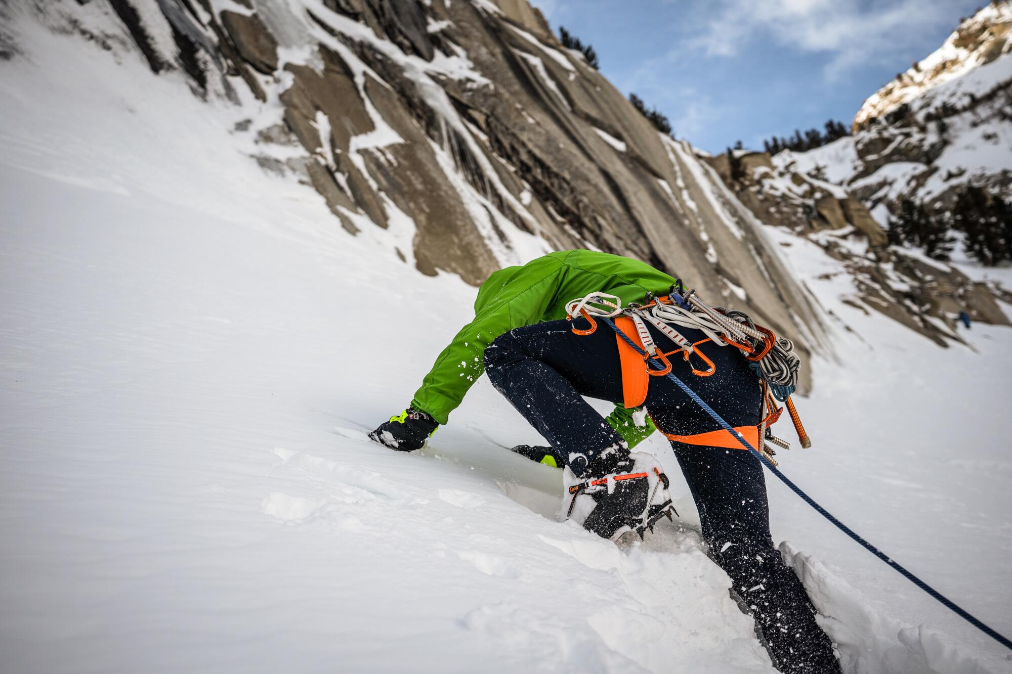 A person wearing crampons walks up a snowy mountain. 