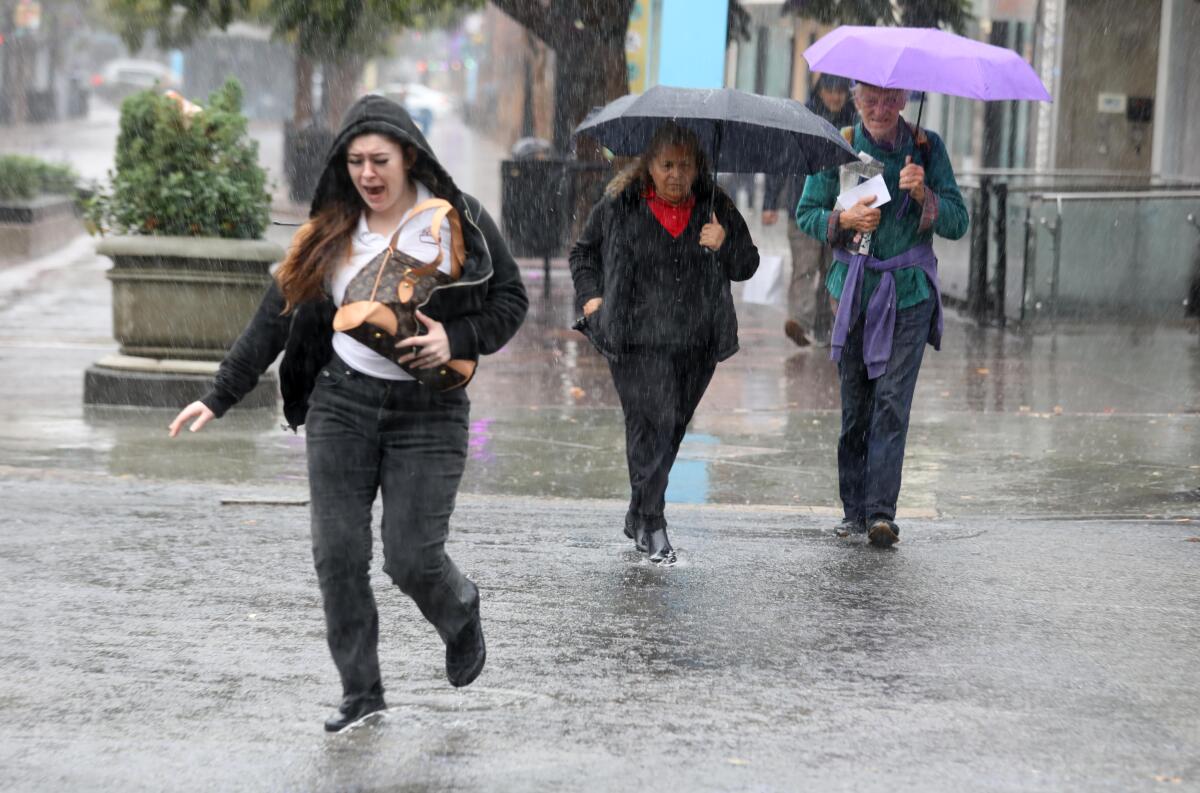 People brave a morning downpour as they make their way across a Santa Monica intersection on Wednesday.