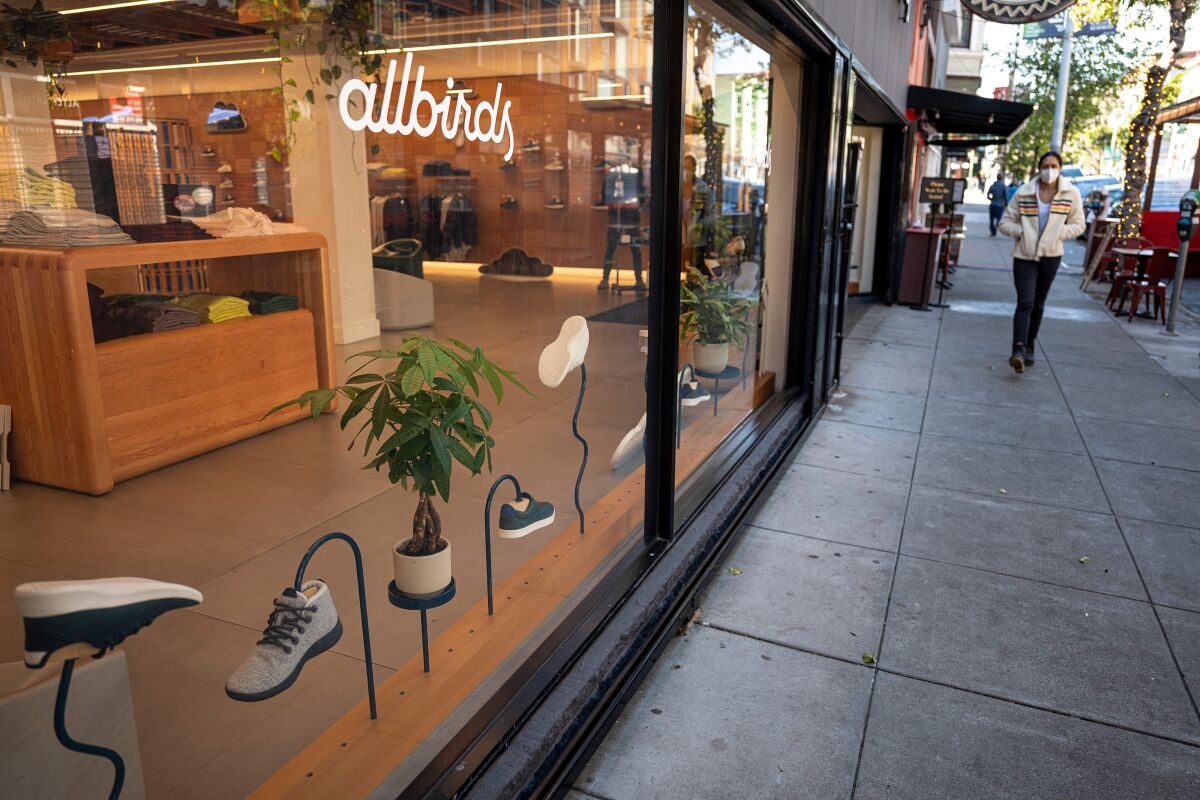 A pedestrian wearing a protective mask walks past an Allbirds store in San Francisco in 2021. 