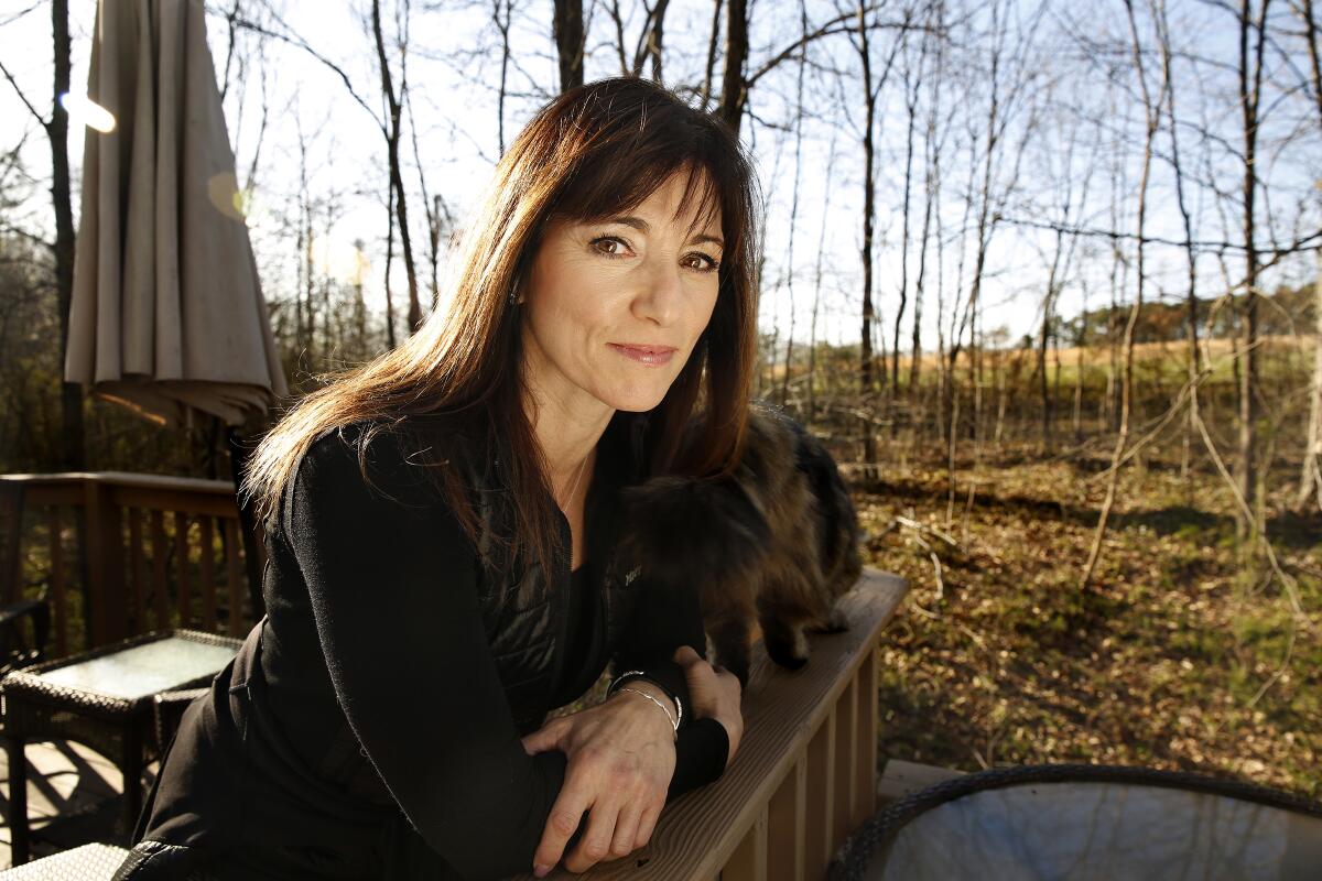 Peggy Hayes leaning against the railing of a patio in a wooded area