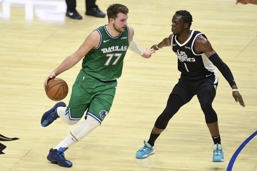 Dallas Mavericks guard Luka Doncic, left, drives towards the basket as Los Angeles Clippers guard.