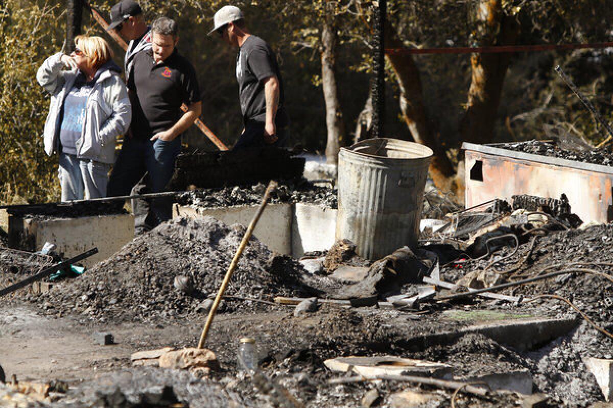 Cabin owner Candy Martin and her sons look through the charred debris of the mountain home where days earlier former cop Christopher Dorner died after a shootout with officers.