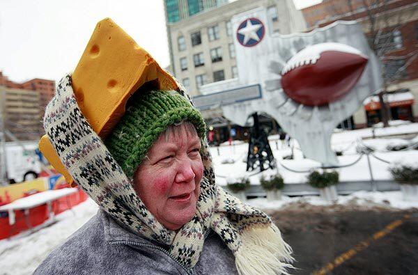 Caroline Fralia of Fort Worth uses a scarf to secure her foam cheesehead hat in Sundance Square.