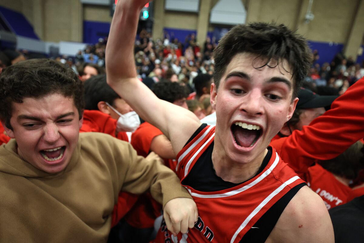 Harvard-Westlake's Brady Dunlap, right, celebrates with fans after a win over Sierra Canyon on Feb. 18, 2022.