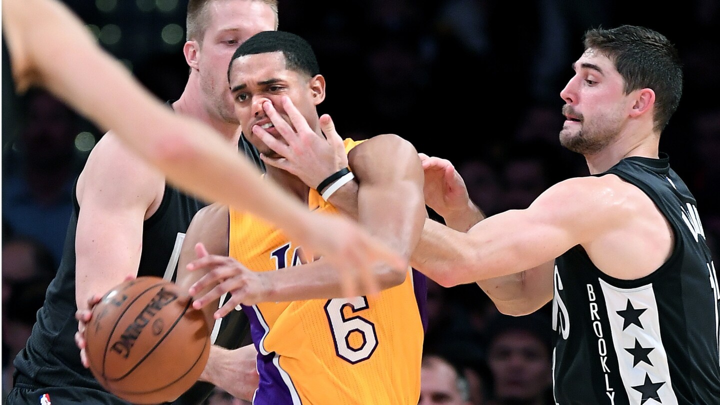 Lakers Jordan Clarkson gets a finger to the nose by Nets Joe Harris, right, as Justin Hamilton tries to help on defense in the 4th quarter.