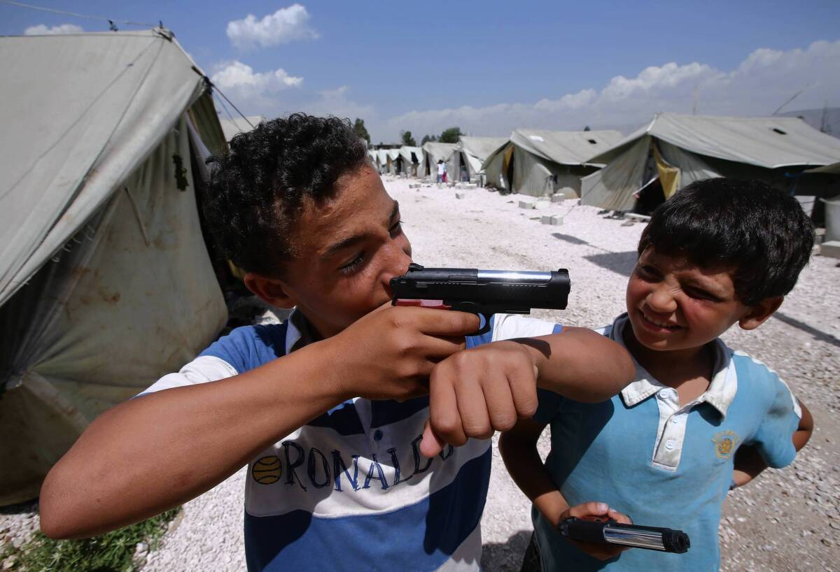 Jamal, an 11-year-old Syrian refugee, points his toy gun while playing with a friend at a refugee camp in the Lebanese town of Marj.