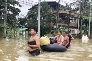 Volunteers push a woman with her belongings on inner-tube along a flooded road in Bago, Myanmar, about 80 kilometers (50 miles) northeast of Yangon, Friday, Aug. 11, 2023. (AP Photo)