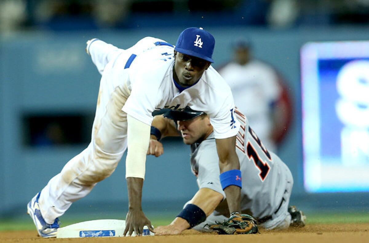 Dodgers second baseman Dee Gordon tumbles over Detroit's Tyler Collins after making a throw to first base to complete a double play in the eighth inning Wednesday night at Dodger Stadium.